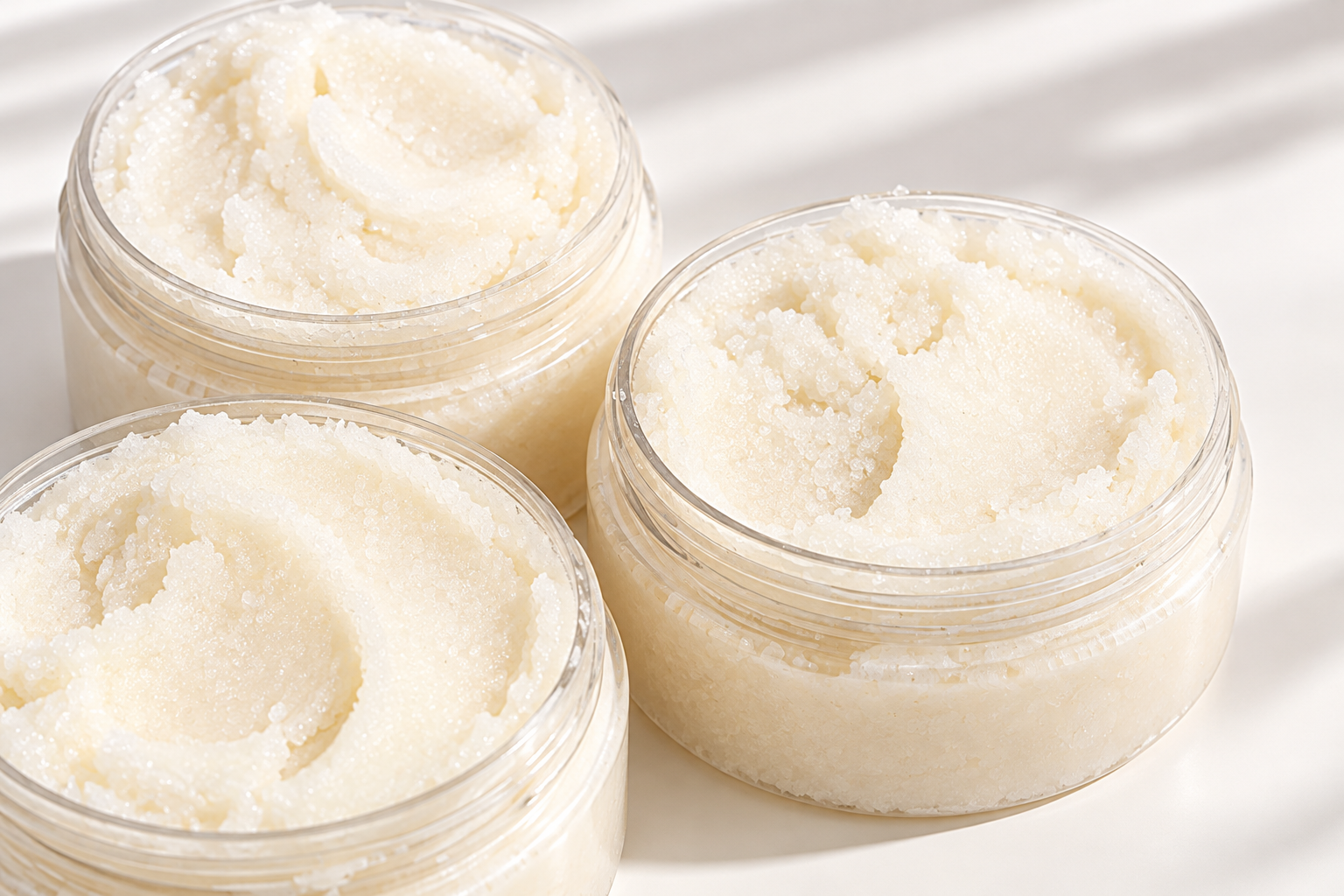 Blissfully Pure fragrance-free sugar scrub in clear jars with natural ivory scrub and white cream background